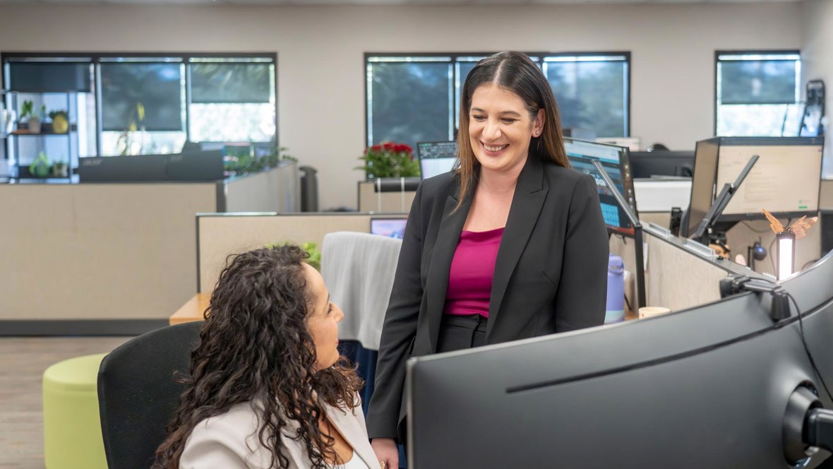 Trailer Bridge employees sitting laughing while working together at their desk.