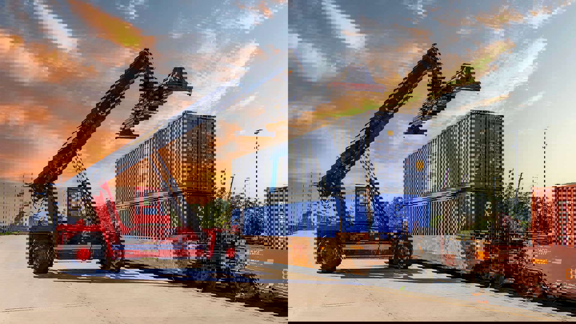 A crane vehicle lines up to move a shipping container off a train.