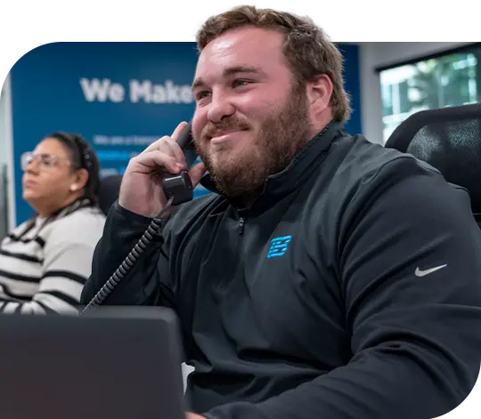 A smiling Trailer Bridge employee speaking to someone on the phone.