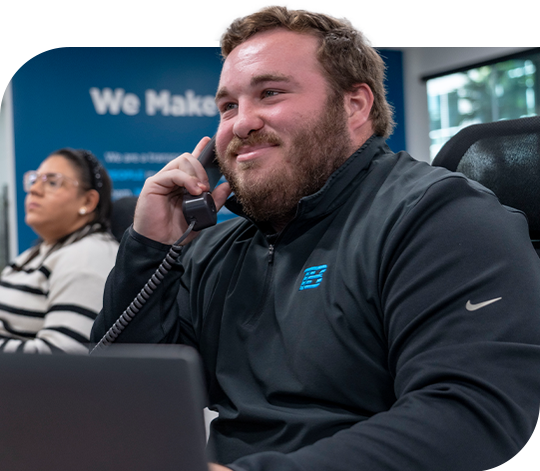 A smiling Trailer Bridge employee speaking to someone on the phone.