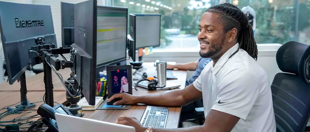 A trailer Bridge employee smiles while working at a computer.