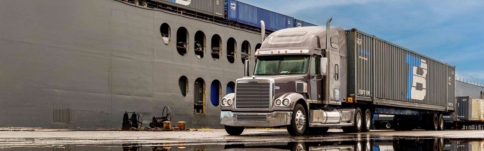 A Trailer Bridge semi-truck waits at a dock.