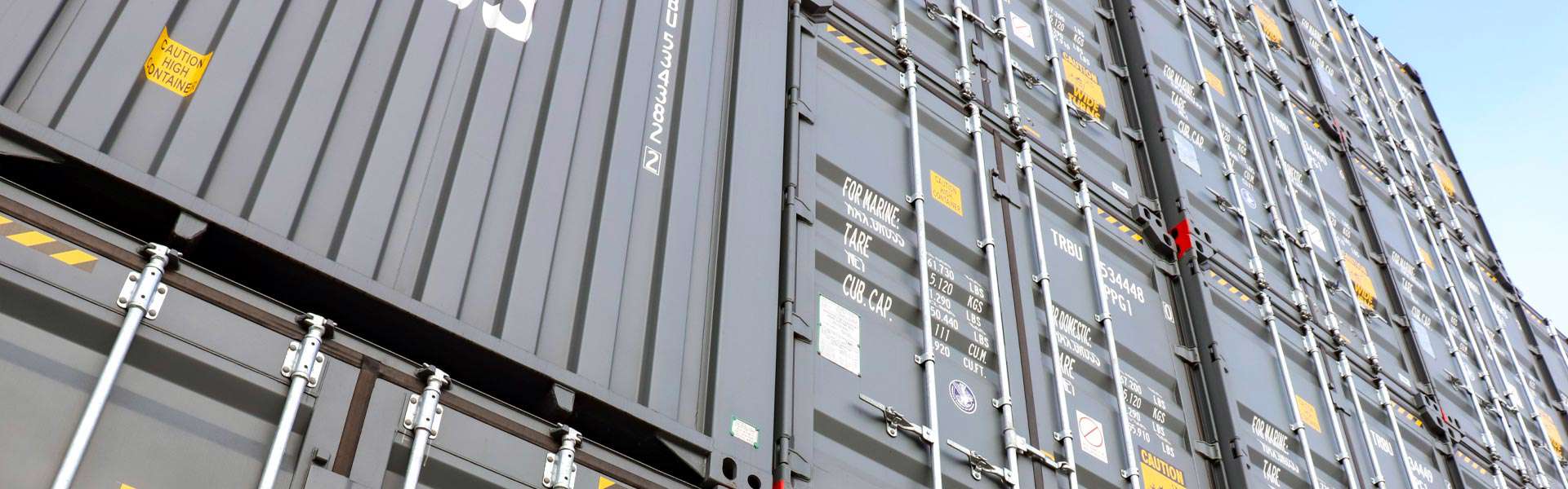 An angled shot looking up at a stack of shipping containers.