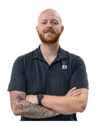 A Trailer Bridge employee stands, arms crossed and smiling at camera.