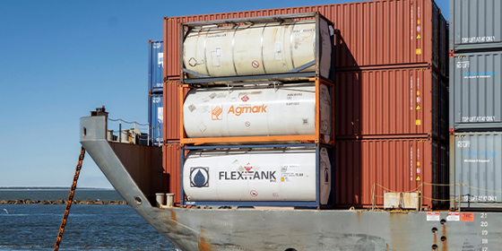 A barge carries stacks of shipping containers and tanks of liquid.