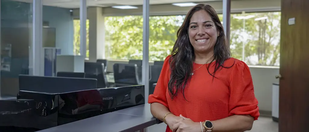 A Trailer Bridge employee stands in an office and smiles at the camera.