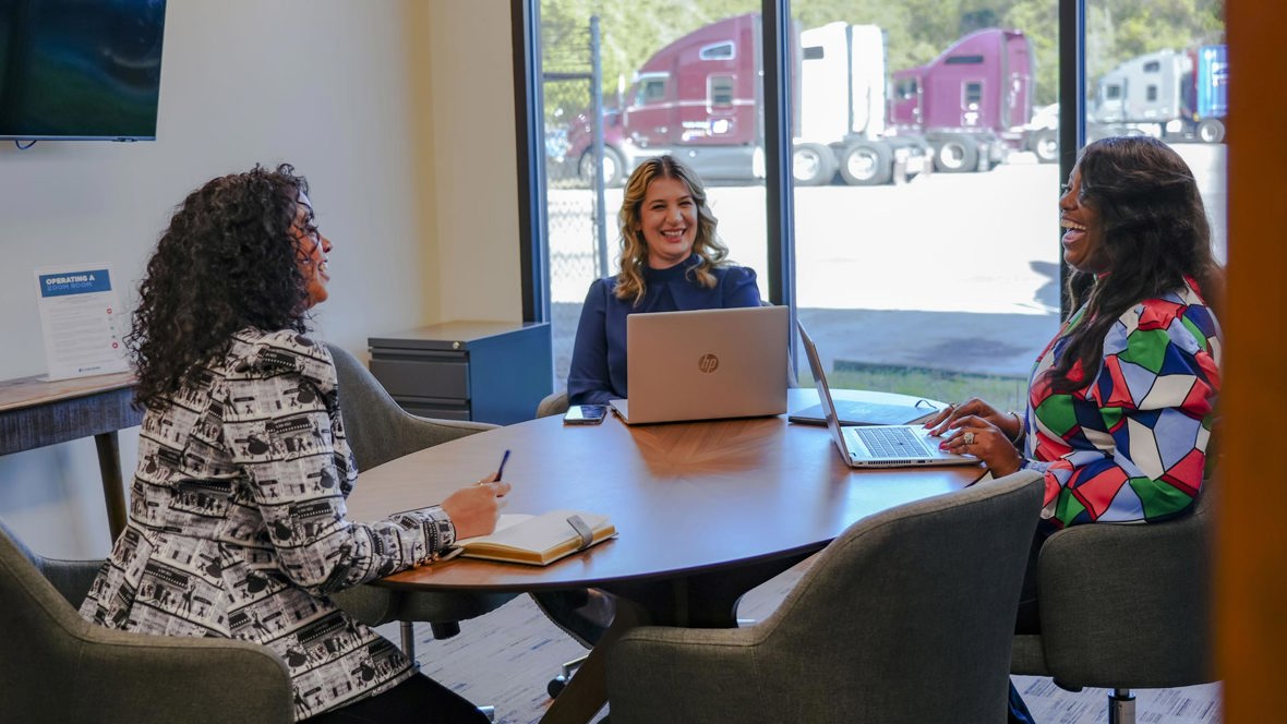 Three people have a meeting at a table.