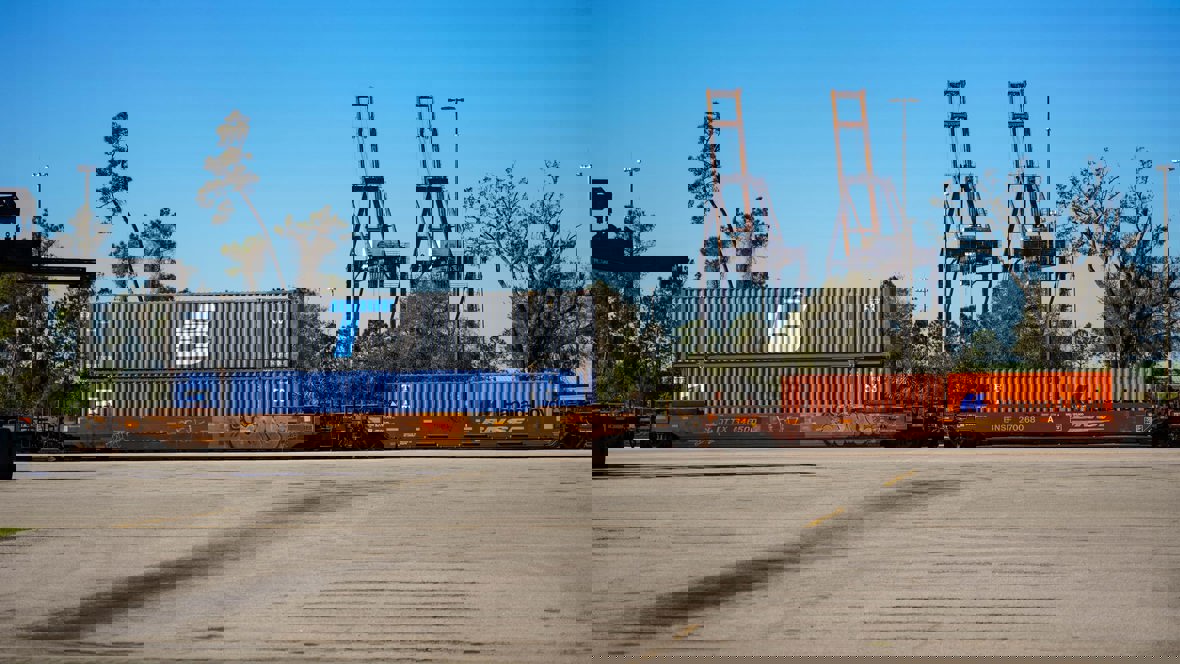 Several shipping containers being transported on a train, some of them with the Trailer Bridge logo.