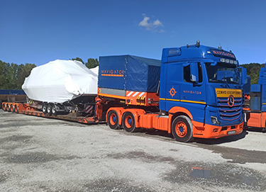 A covered piece of equipment is being transported on a truck.