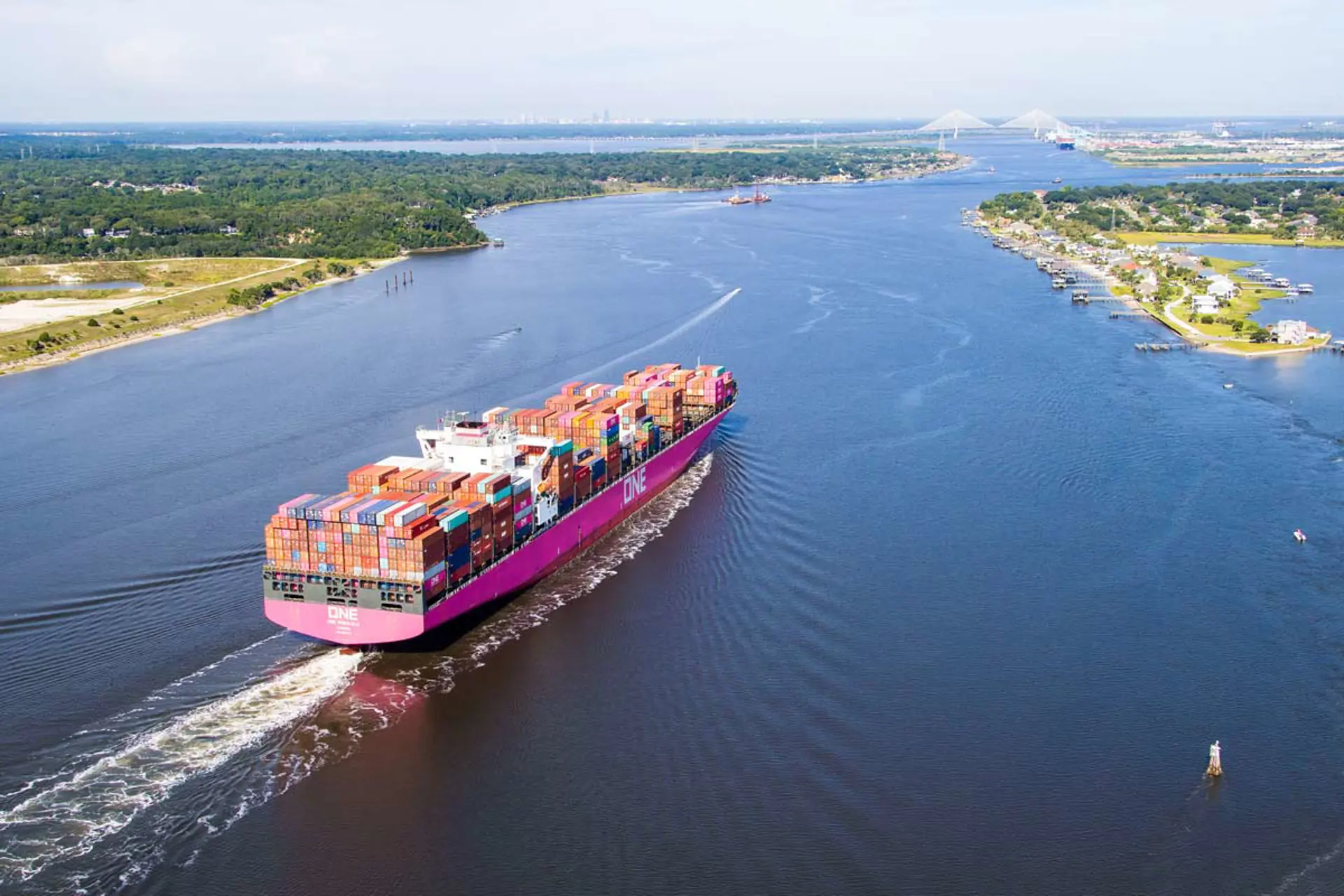 A ship carries containers out to sea.