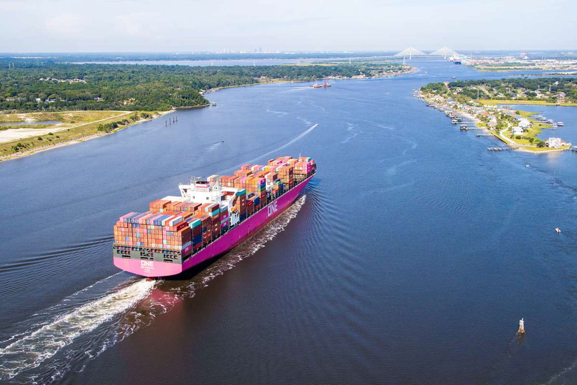 A ship carries containers out to sea.