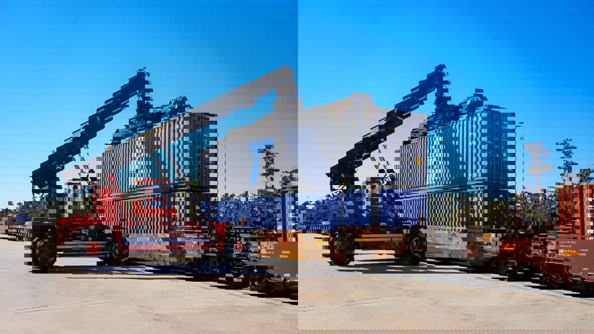 A crane lifts a container off a train.