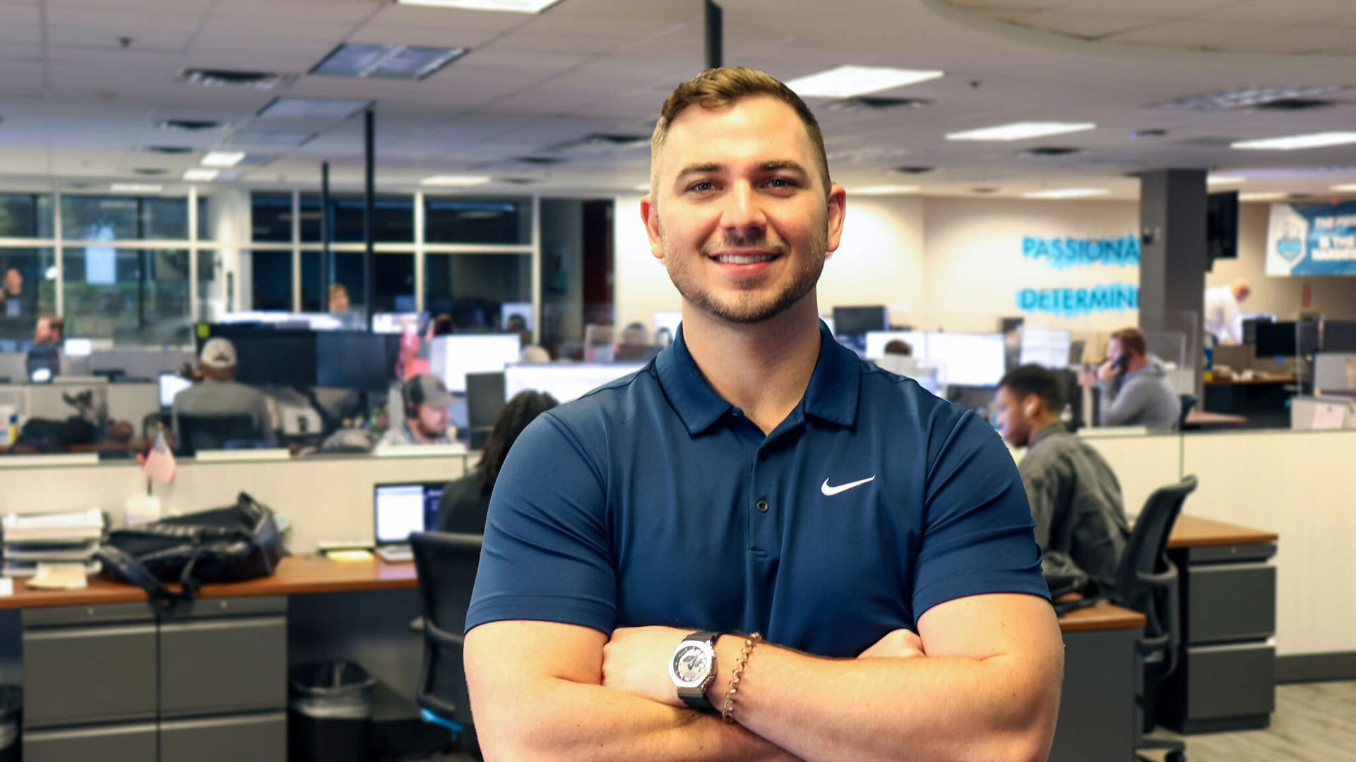 A smiling Trailer Bridge employee stands with arms crossed.