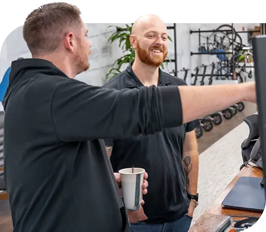 Two Trailer Bridge employees discuss the contents on a computer monitor.