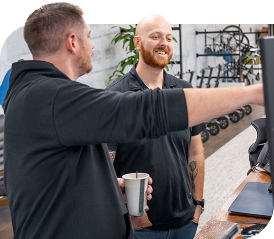 Two Trailer Bridge employees discuss the contents on a computer monitor.
