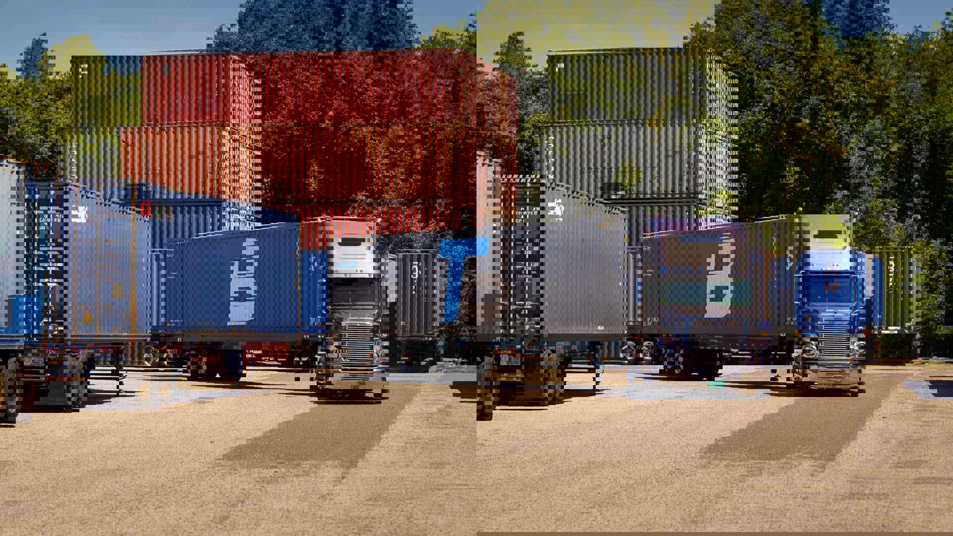 A Trailer Bridge truck pulls away from a lot of shipping containers.
