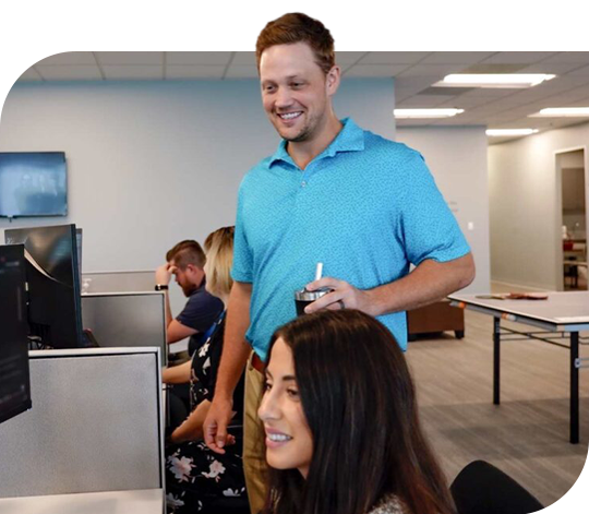 Two Trailer Bridge employees look at a computer screen while smiling.
