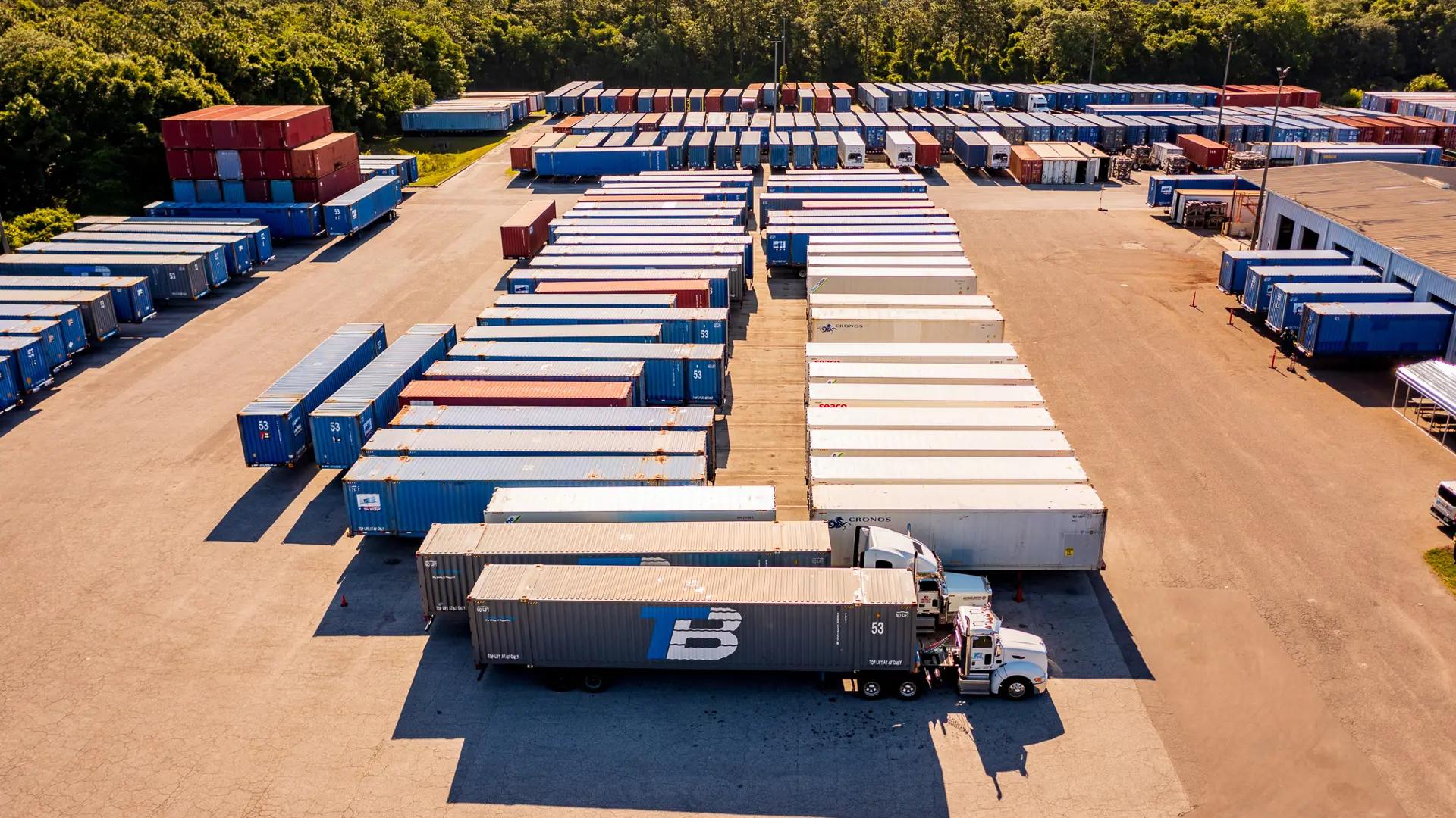 A lot full of shipping trailers with two trucks.