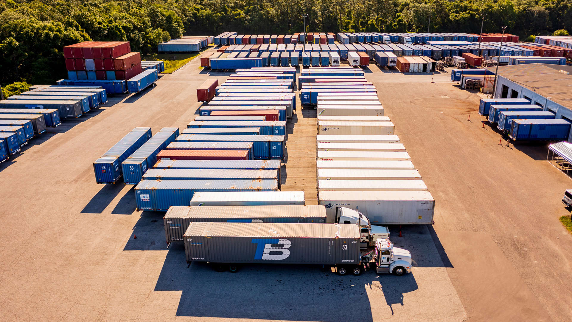 A lot full of shipping trailers with two trucks.