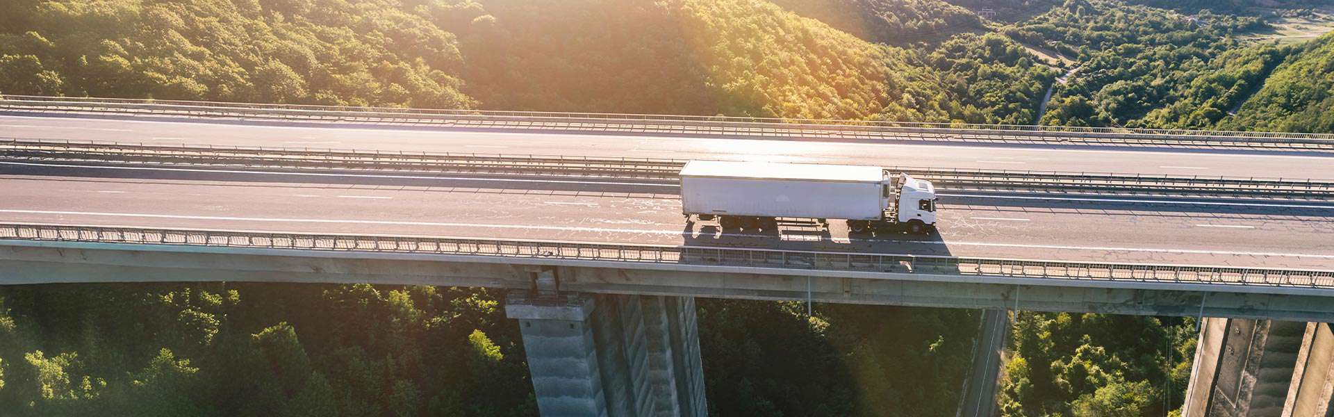 An overhead shot of a semi-truck driving along an empty bridge.