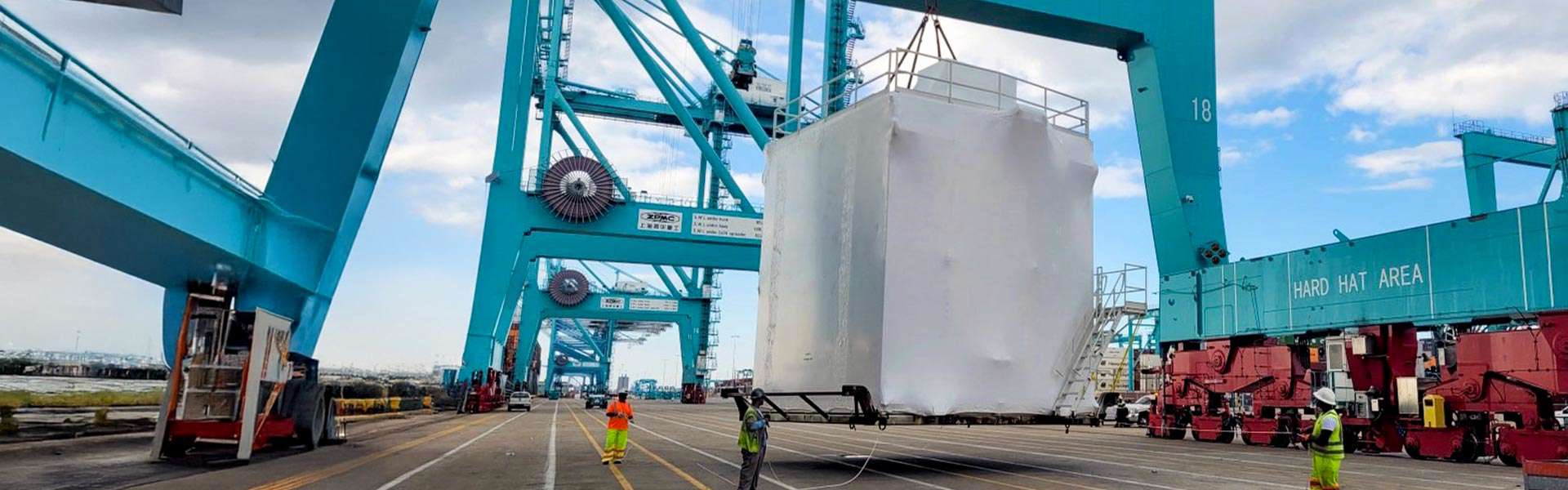 A large, bulky item is being lifted by machinery at a port.
