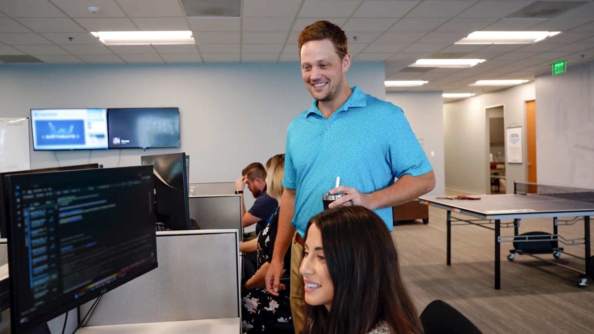 Employees smile while looking at a computer screen in an office.