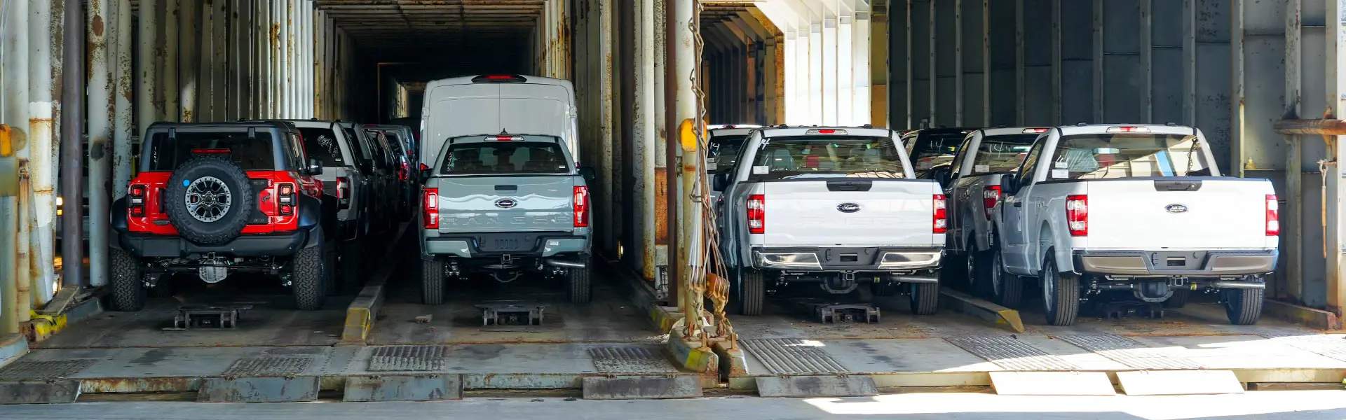Several vehicles are loaded and secured into shipping containers.