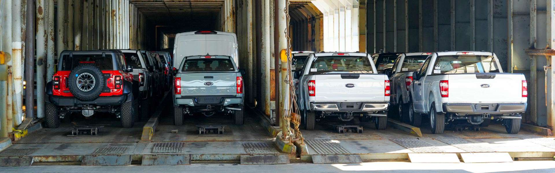 Several vehicles are loaded and secured into shipping containers.